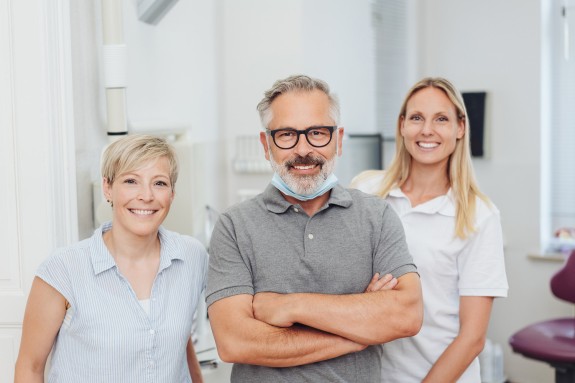 Team an Ärzten lächelt selbstbewusst in die Kamera