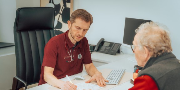 Hr. Bice notiert sich etwas während einer Beratung eines Patienten