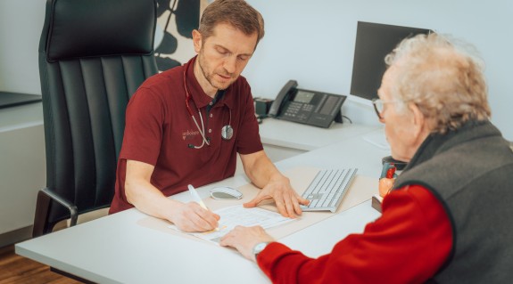 Hr. Bice notiert sich etwas während einer Beratung eines Patienten