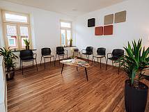 Wartezimmer mit Prakett, Planzen und schwarzen Stühlen